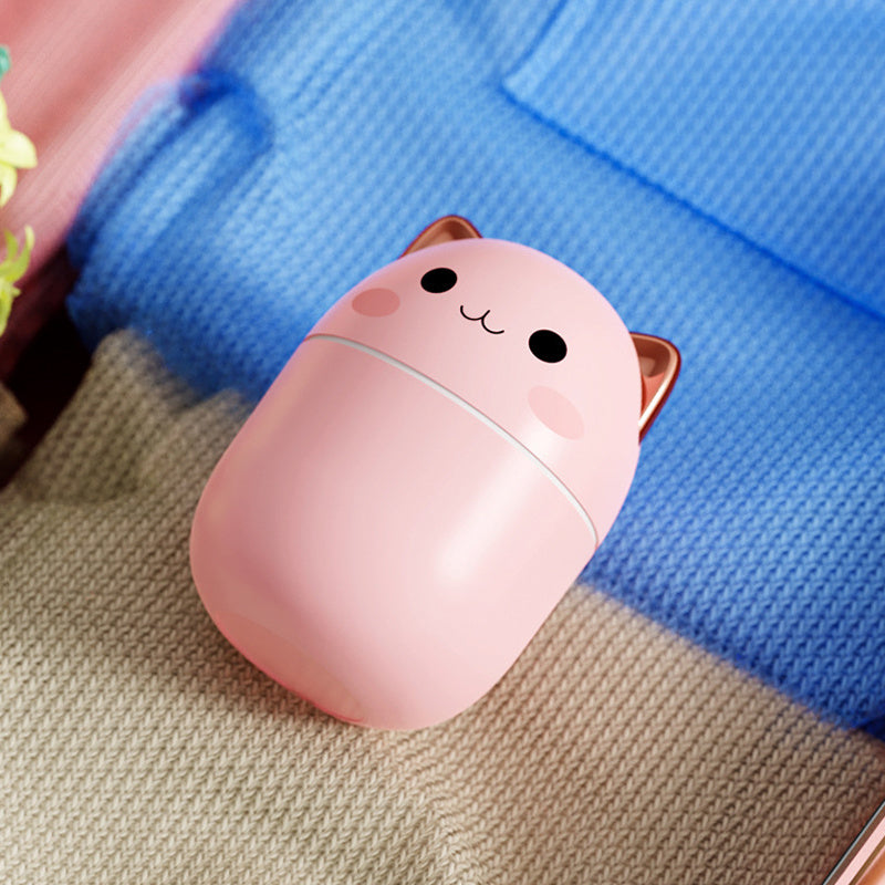 Travel-size pink cat Air Humidifier resting on knitted blanket, 200 ml USB aroma diffuser ideal for dry air